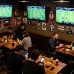 Monitor displaying kết quả bóng đá while sports betting patrons cheer during live matches.
