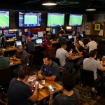 Tỷ Lệ Bóng Đá displayed on screens in a vibrant sports bar betting environment, showcasing live matches.