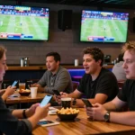 Excited patrons engaging in sports betting activity at cm88's lively venue, with vibrant screens and dynamic social atmosphere.