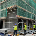 Workers installing commercial scaffolding on a building, ensuring safety and efficiency during renovation.